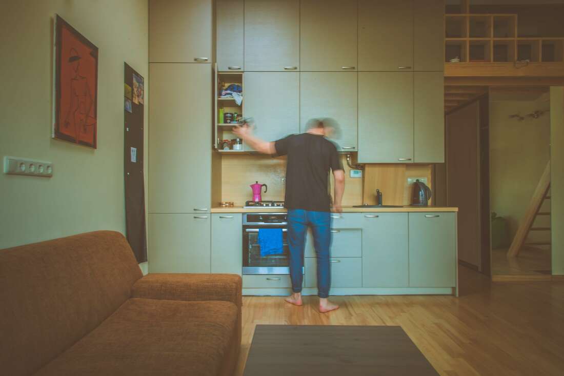 Man standing in front of dated kitchen cupboards that are teal and need a renovation