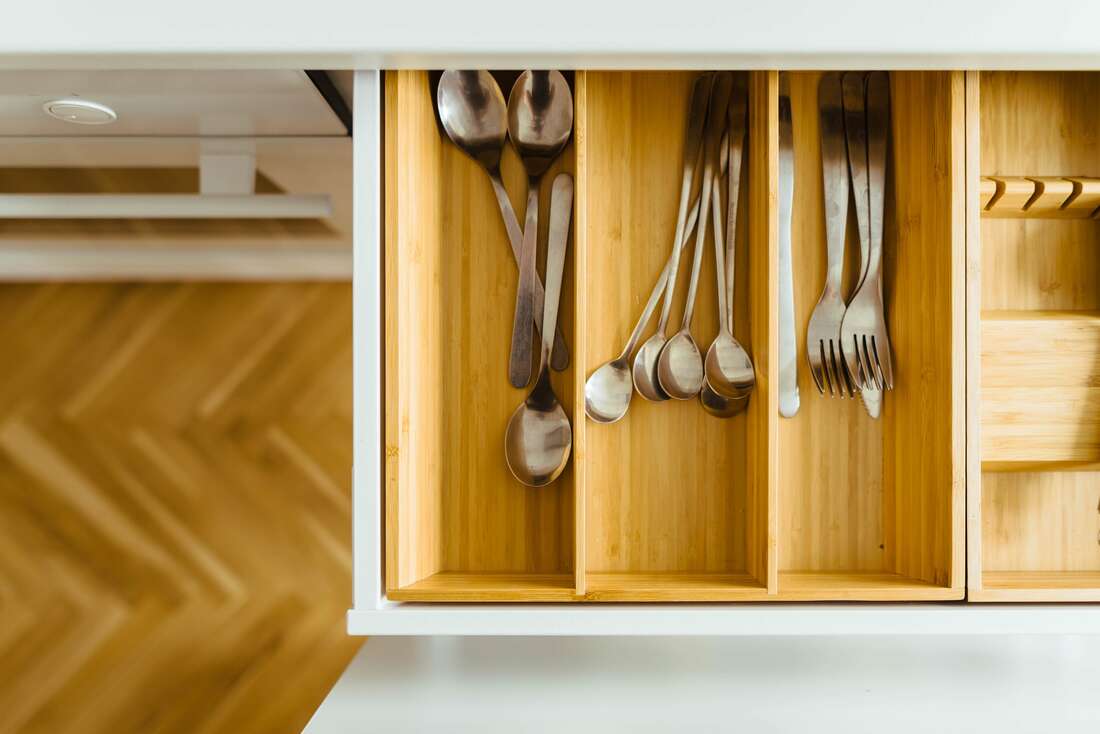 Wooden kitchen drawer with forks and spoons lined up inside